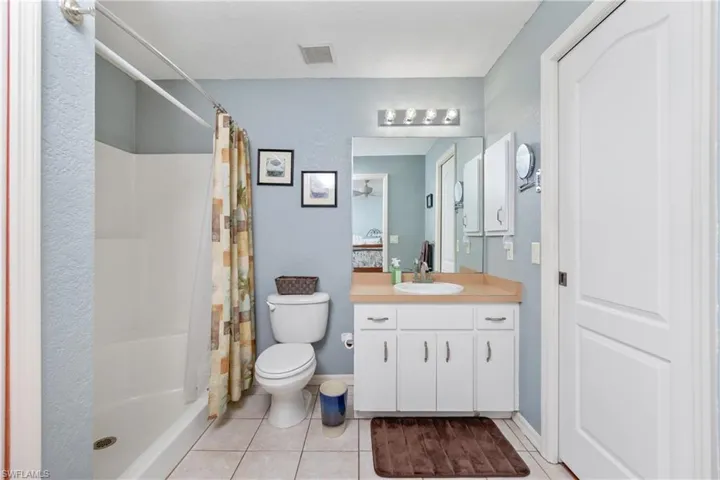 Bathroom featuring visible vents, a shower with shower curtain, toilet, tile patterned flooring, and vanity