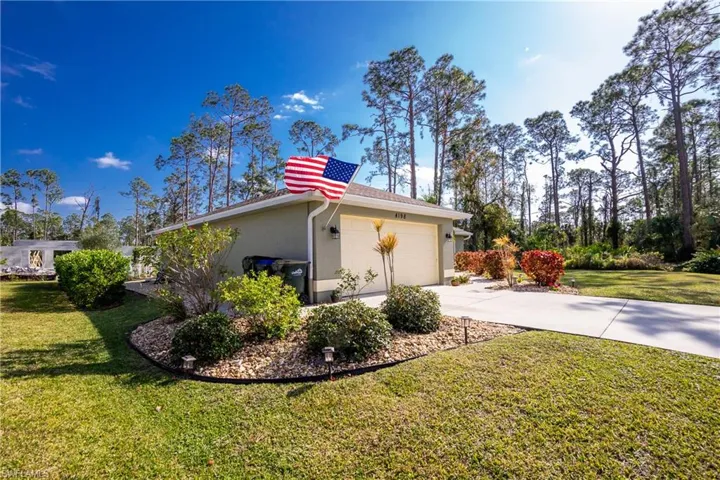 View of property exterior with a yard, driveway, a garage, and stucco siding