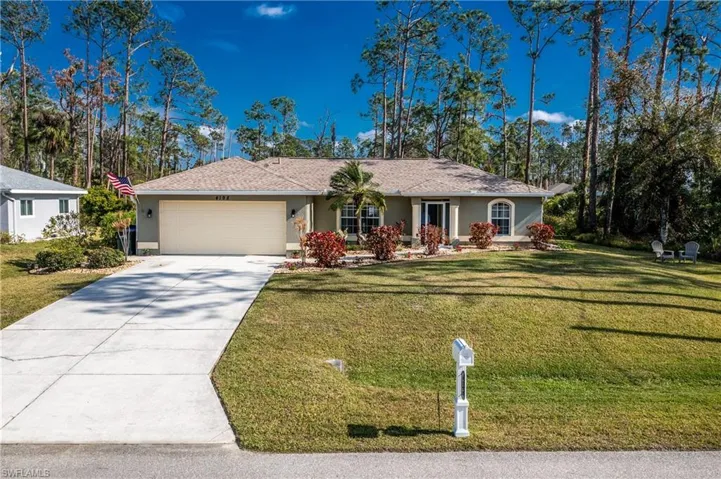 Ranch-style house with a front yard, concrete driveway, an attached garage, and stucco siding