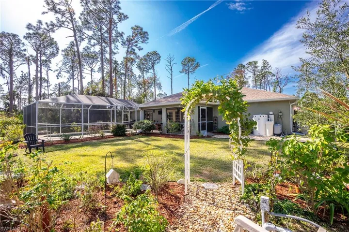 Back of property featuring a yard, glass enclosure, and stucco siding