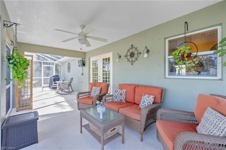 Living room featuring a ceiling fan, a sunroom, heating unit, a textured ceiling, and french doors