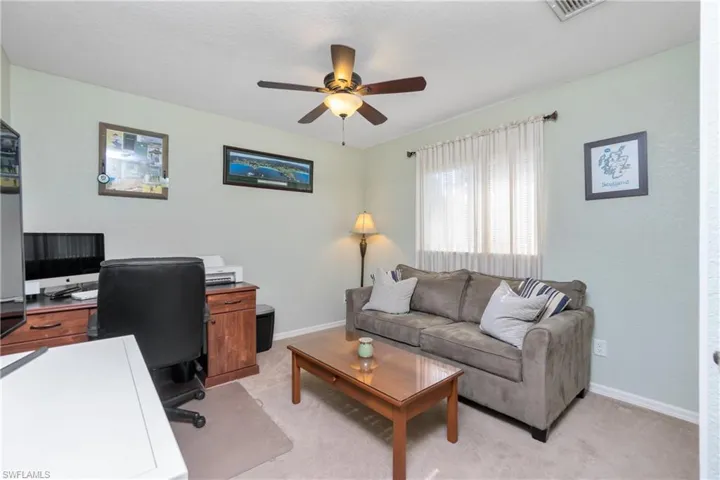 Office with light carpet, baseboards, visible vents, and a ceiling fan