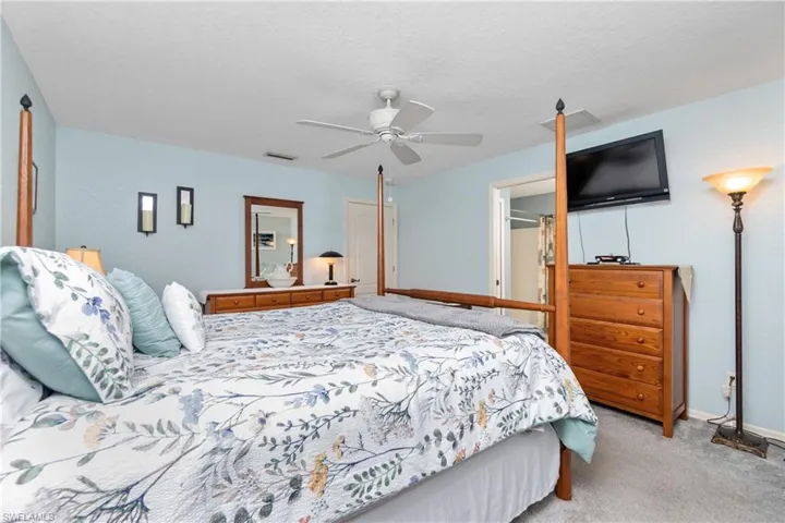 Carpeted bedroom with baseboards, ceiling fan, visible vents, and a textured ceiling