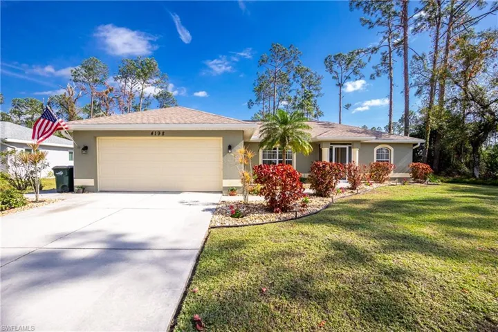 Ranch-style home featuring an attached garage, driveway, a front lawn, and stucco siding