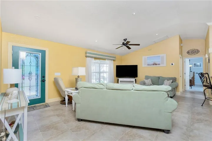 Living room featuring visible vents, vaulted ceiling, baseboards, and ceiling fan