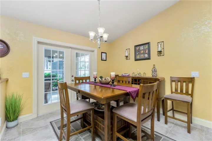 Dining room with an inviting chandelier, baseboards, vaulted ceiling, and french doors