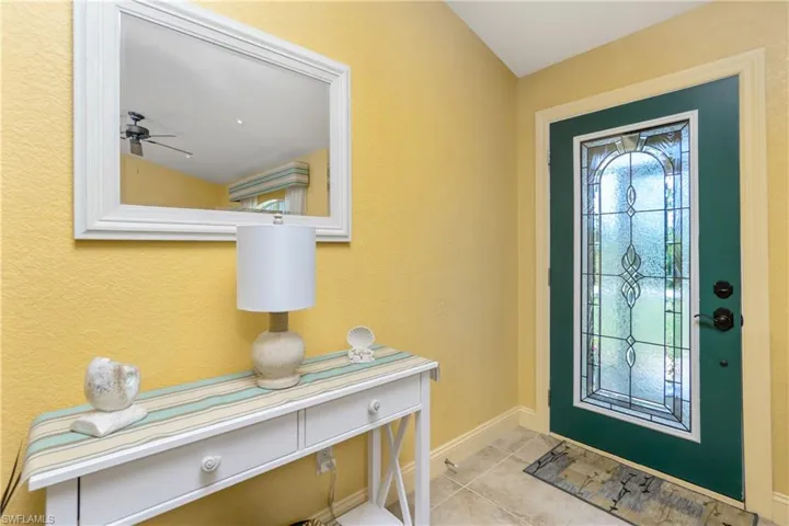 Entryway featuring light tile patterned floors, baseboards, vaulted ceiling, and a ceiling fan
