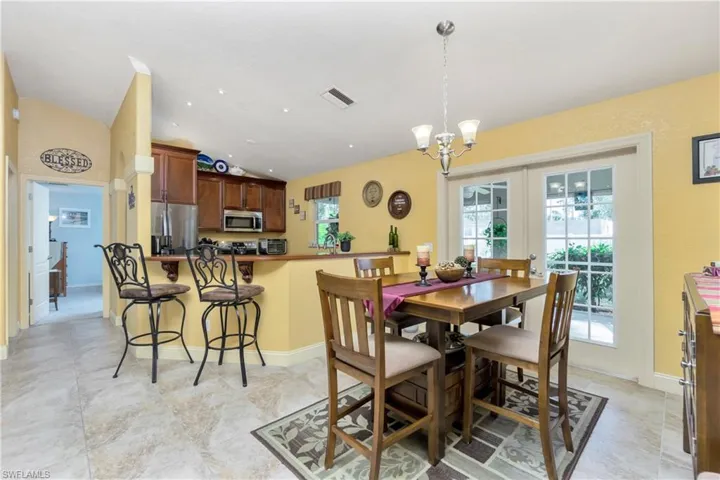 Dining room with french doors, a notable chandelier, lofted ceiling, visible vents, and baseboards