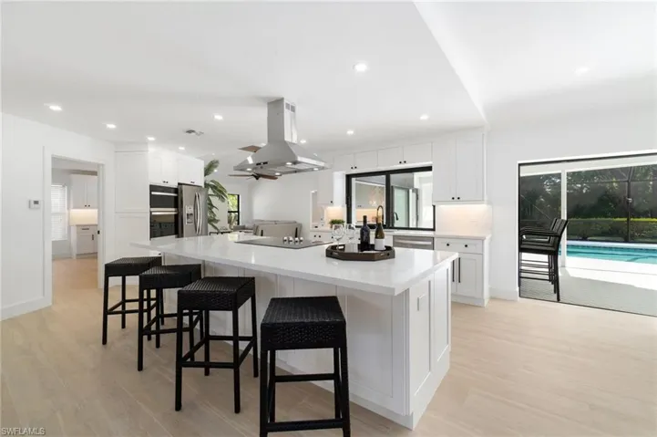 Kitchen with a spacious island, white slow-close cabinets, island exhaust hood, and stainless steel appliances