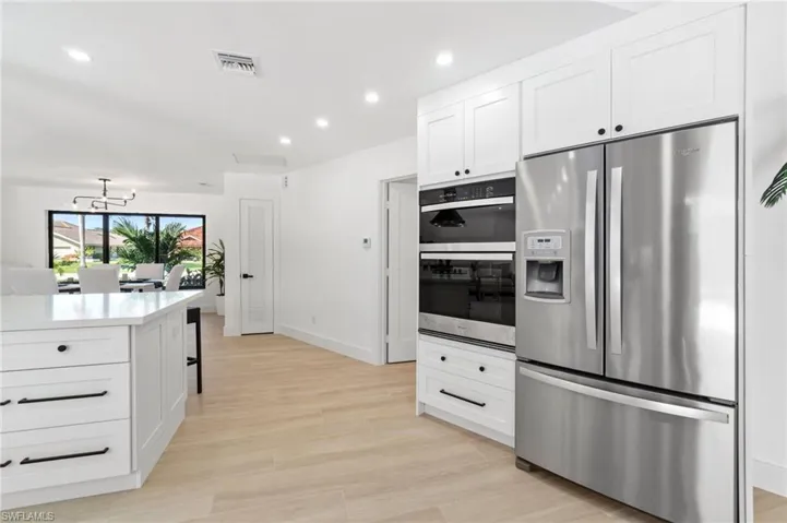 Kitchen featuring appliances with stainless steel finishes, quartz countertops, white cabinetry, and recessed lighting