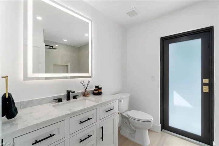 Guest bath with a walk in shower, toilet, recessed lighting, vanity, and french door leading to lanai and pool.