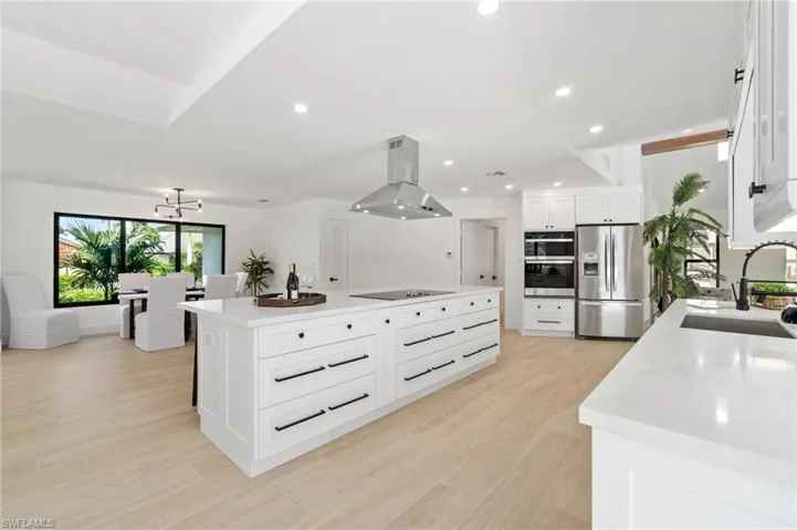 Kitchen featuring a kitchen island, appliances with stainless steel finishes, island exhaust hood, white slow-close cabinetry, and a sink