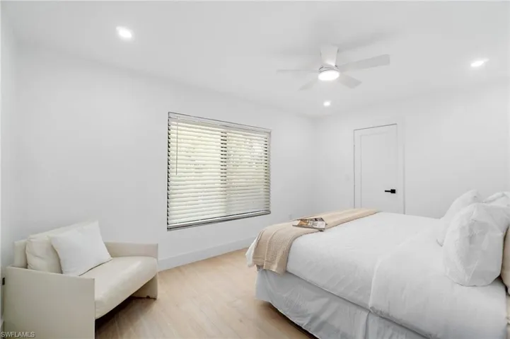 Guest bedroom featuring a king-sized bed, recessed lighting, upgraded baseboards, ceiling fan, and light wood finished floors