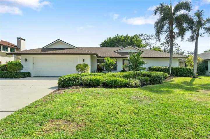 View of front of home featuring driveway, a front lawn, an attached garage