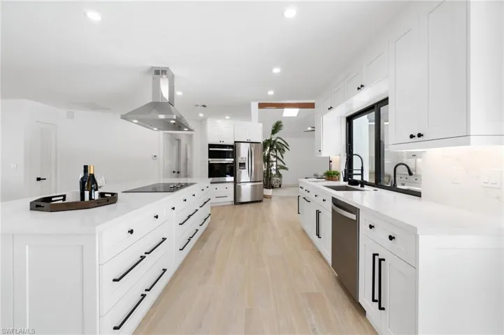 Kitchen with stainless steel appliances, island exhaust hood, light countertops, and white cabinets