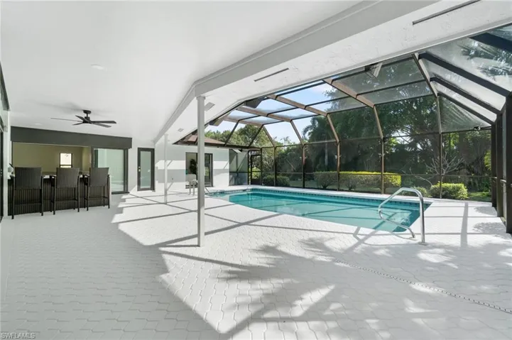 Outdoor pool featuring a ceiling fan, a lanai, a patio area, and an outdoor bar