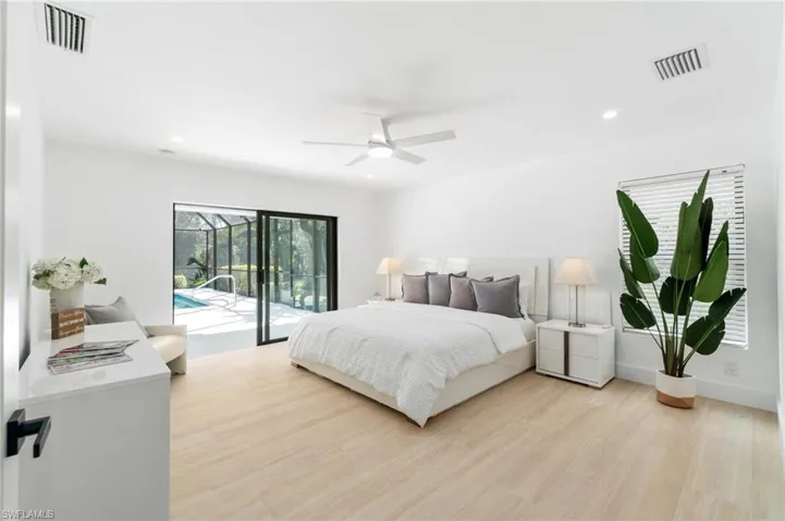 Primary bedroom featuring access to exterior lanai, light wood-style flooring, and recessed lighting