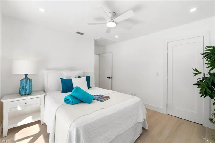 Guest bedroom featuring queen-size bed, light wood-style floors, attic access, and recessed lighting
