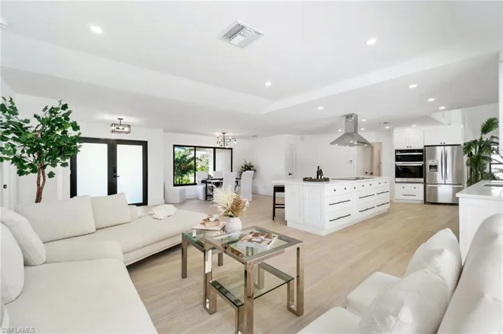Living area featuring light wood-style floors, recessed lighting, and a notable chandelier