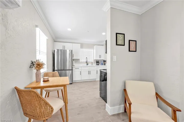 Kitchen featuring white cabinetry, crown molding, freestanding refrigerator, and a textured wall