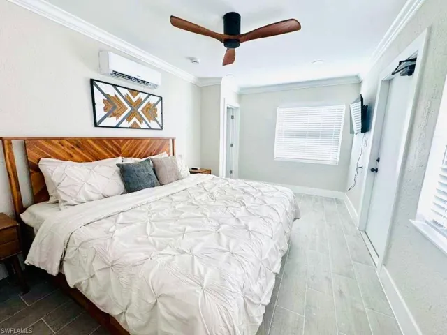 Bedroom featuring ornamental molding, wood tiled floors, a ceiling fan, and a wall unit AC