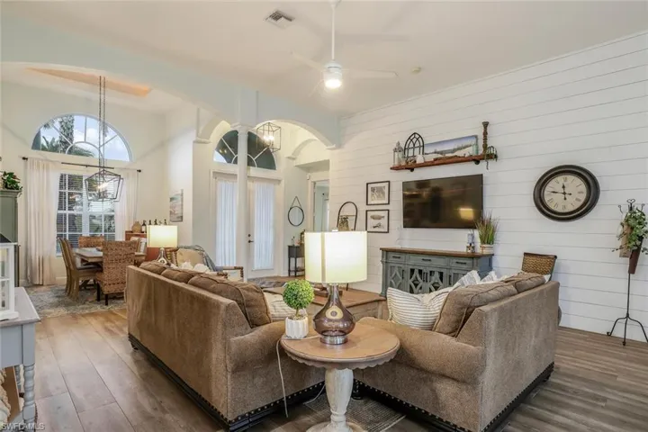 Living/Family room with a ceiling fan, wood finished floors, arched walkways and a high ceiling,