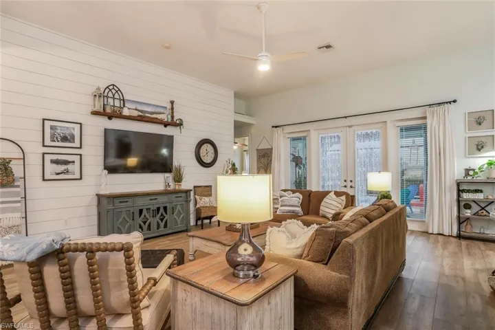 Living/Family room featuring french doors, a ceiling fan, hardwood / wood-style flooring, and wood walls