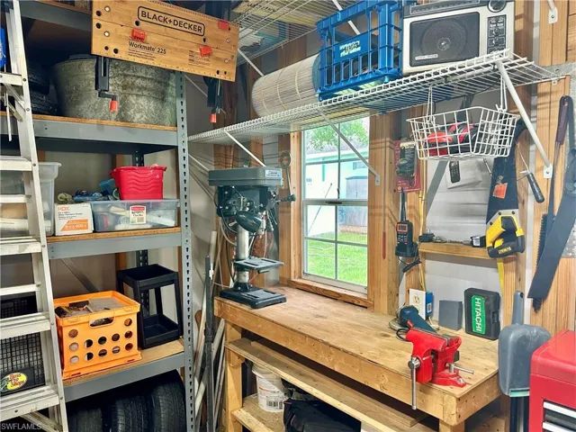 Dedicated workspace featuring a built-in wooden workbench, a window providing natural light, and integrated wall shelving