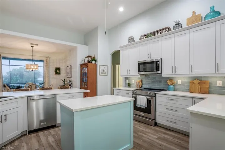 Kitchen featuring stainless steel appliances, white cabinets, a center island, and light wood finished floors