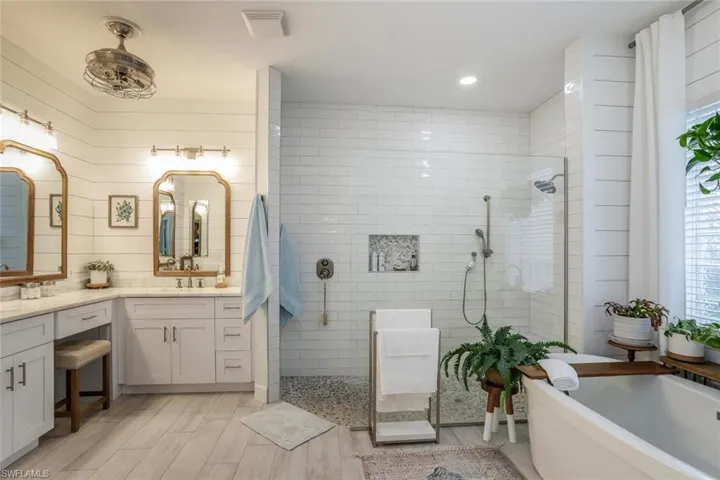 Owner Bathroom with a freestanding bath, walk in shower, double vanity, wood finish floors, and healthy amount of natural light