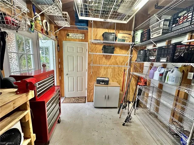 Utility space featuring plywood wall paneling and a concrete floor