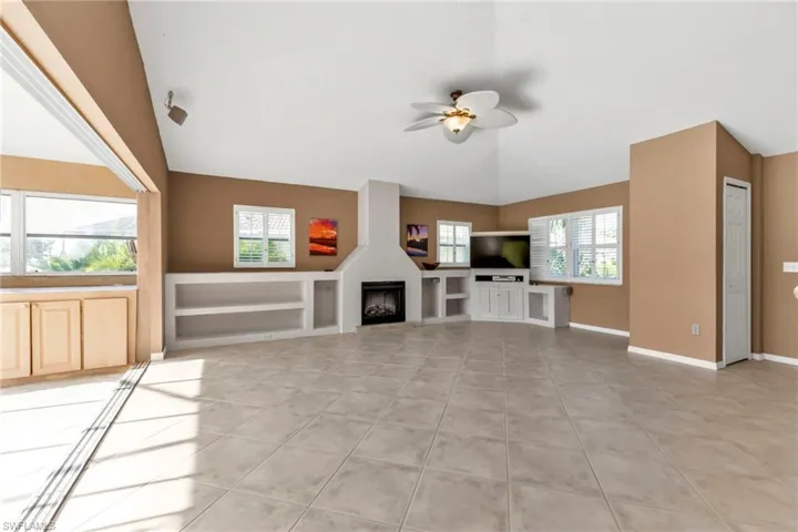 Unfurnished living room with a wealth of natural light, ceiling fan, light tile patterned floors, and high vaulted ceiling
