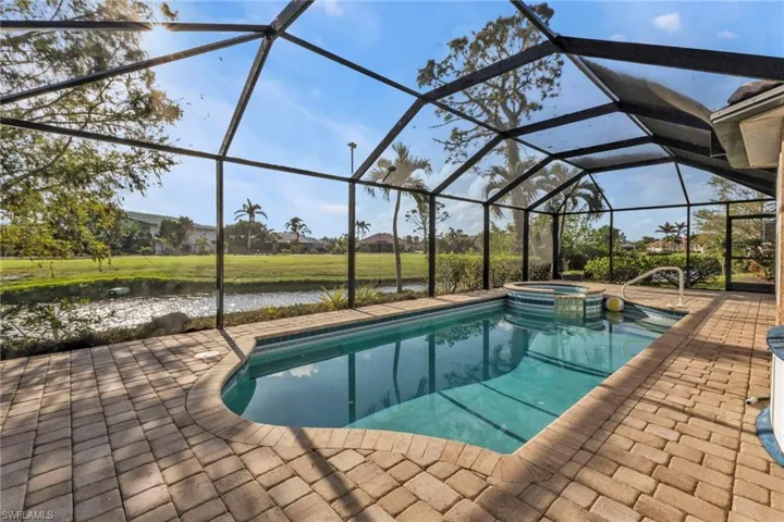 View of pool with an in ground hot tub, a patio, a water view, and a lanai