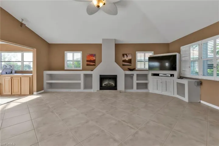 Unfurnished living room with vaulted ceiling, ceiling fan, and a healthy amount of sunlight