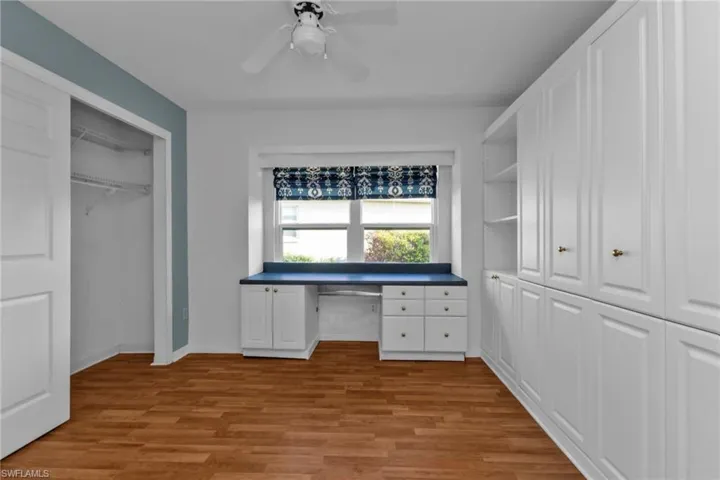 Unfurnished office featuring ceiling fan, light hardwood / wood-style flooring, and built in desk