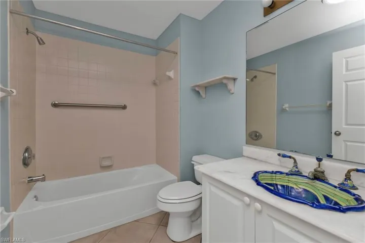 Full bathroom with tile patterned flooring, vanity, toilet, and tiled shower / bath combo