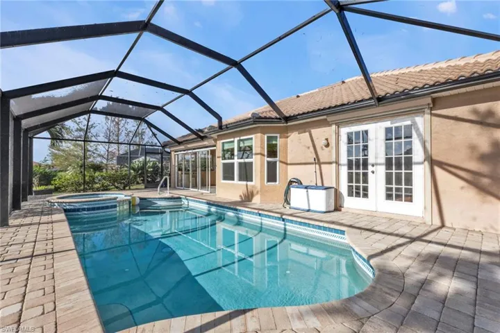 View of swimming pool featuring a patio area, an in ground hot tub, a lanai, and french doors