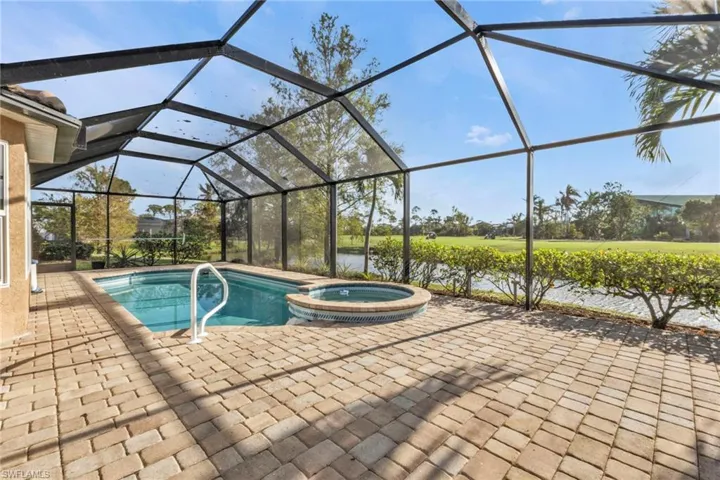 View of pool with glass enclosure, a water view, an in ground hot tub, and a patio area