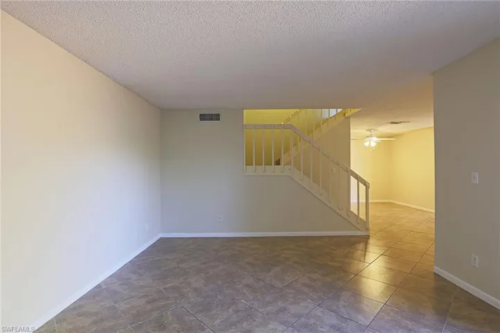 Spare room with a textured ceiling, ceiling fan, and dark tile patterned flooring