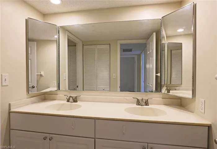 Bathroom with double vanity, a closet, and recessed lighting