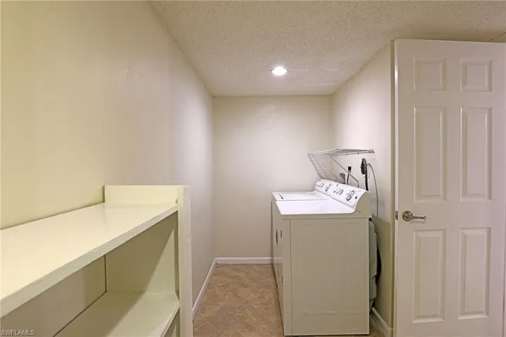 Laundry room with separate washer and dryer, a textured ceiling, and recessed lighting