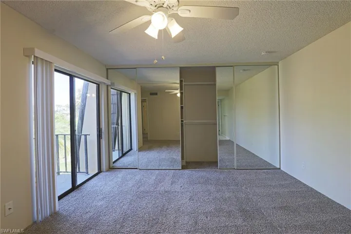 Unfurnished bedroom with access to outside, ceiling fan, carpet floors, a textured ceiling, and a closet