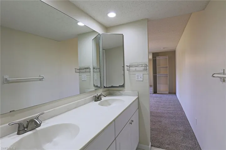 Full bath featuring light colored carpet, double vanity, a textured ceiling, and recessed lighting