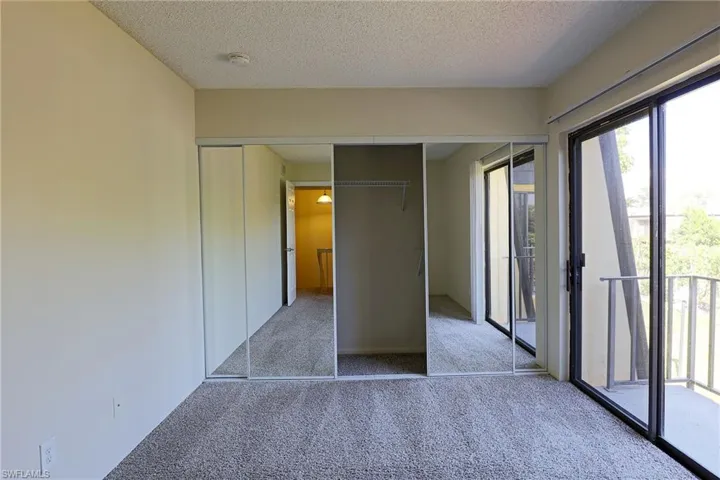 Unfurnished bedroom featuring access to outside, a closet, light carpet, and a textured ceiling