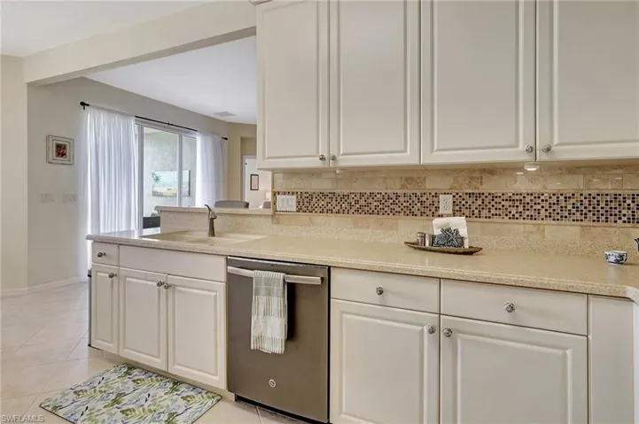 Kitchen with sink, tasteful backsplash, light tile patterned floors, dishwasher, and white cabinets