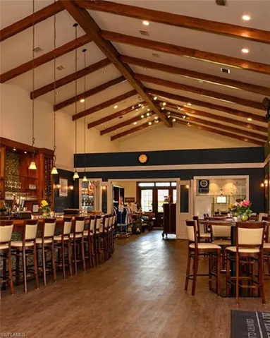Dining room with bar, dark hardwood / wood-style flooring, high vaulted ceiling, and beam ceiling