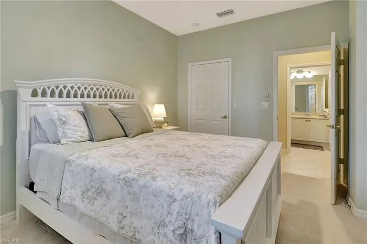Bedroom featuring light colored carpet and ensuite bath