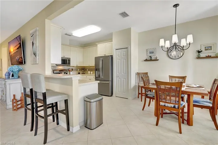 Kitchen featuring stainless steel appliances, kitchen peninsula, hanging light fixtures, and light tile patterned floors