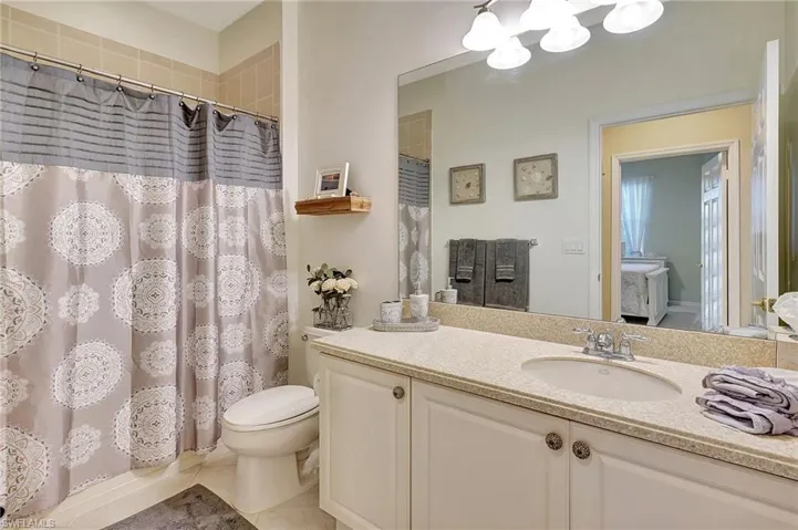Full bathroom with toilet, vanity, shower / bathtub combination with curtain, and tile patterned flooring