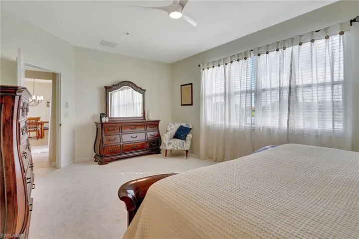 Bedroom featuring light colored carpet and ceiling fan with notable chandelier